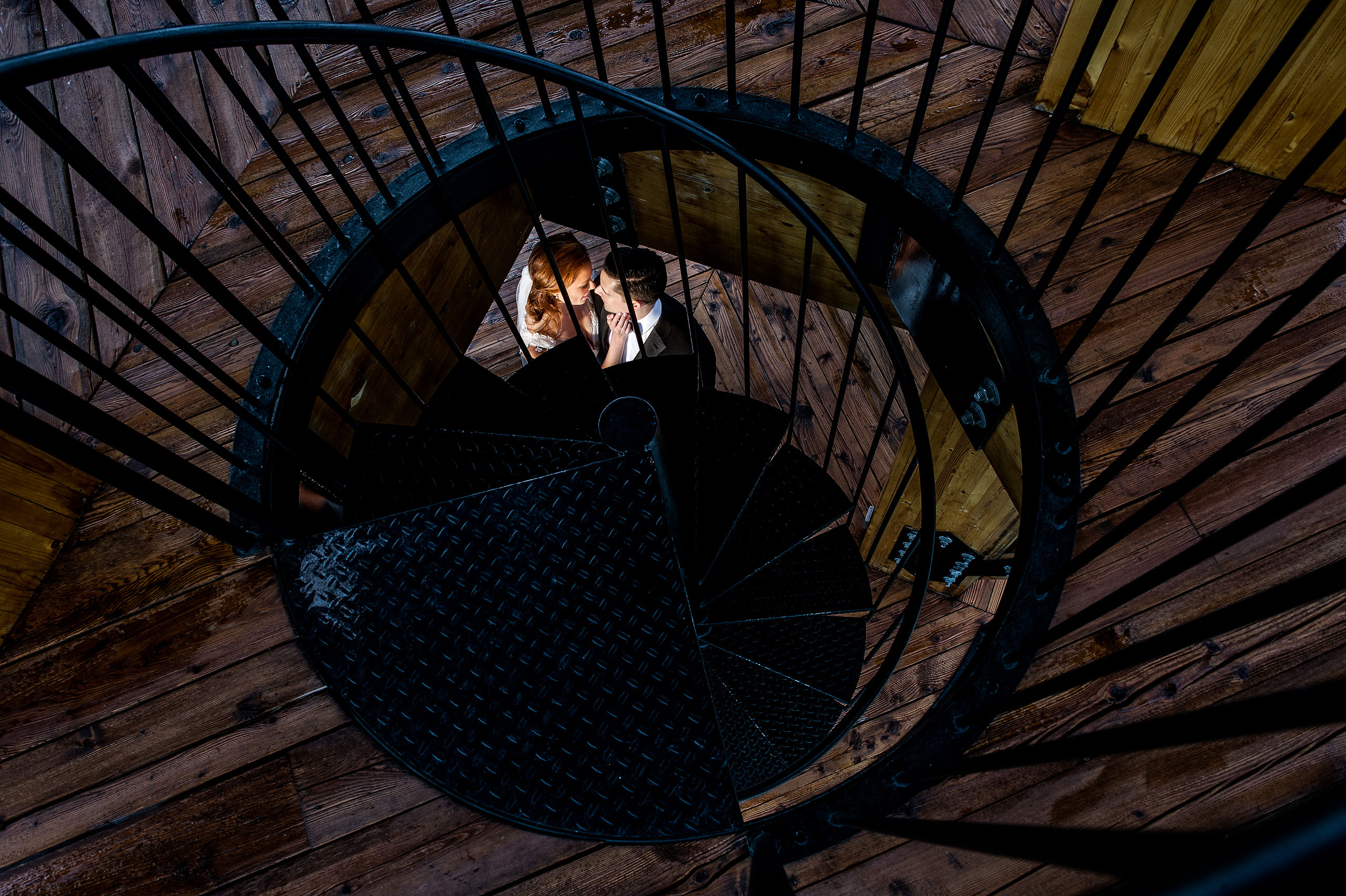 a bride and groom embracing below some stairs at Priddis Azuridge Wedding by sean leblanc