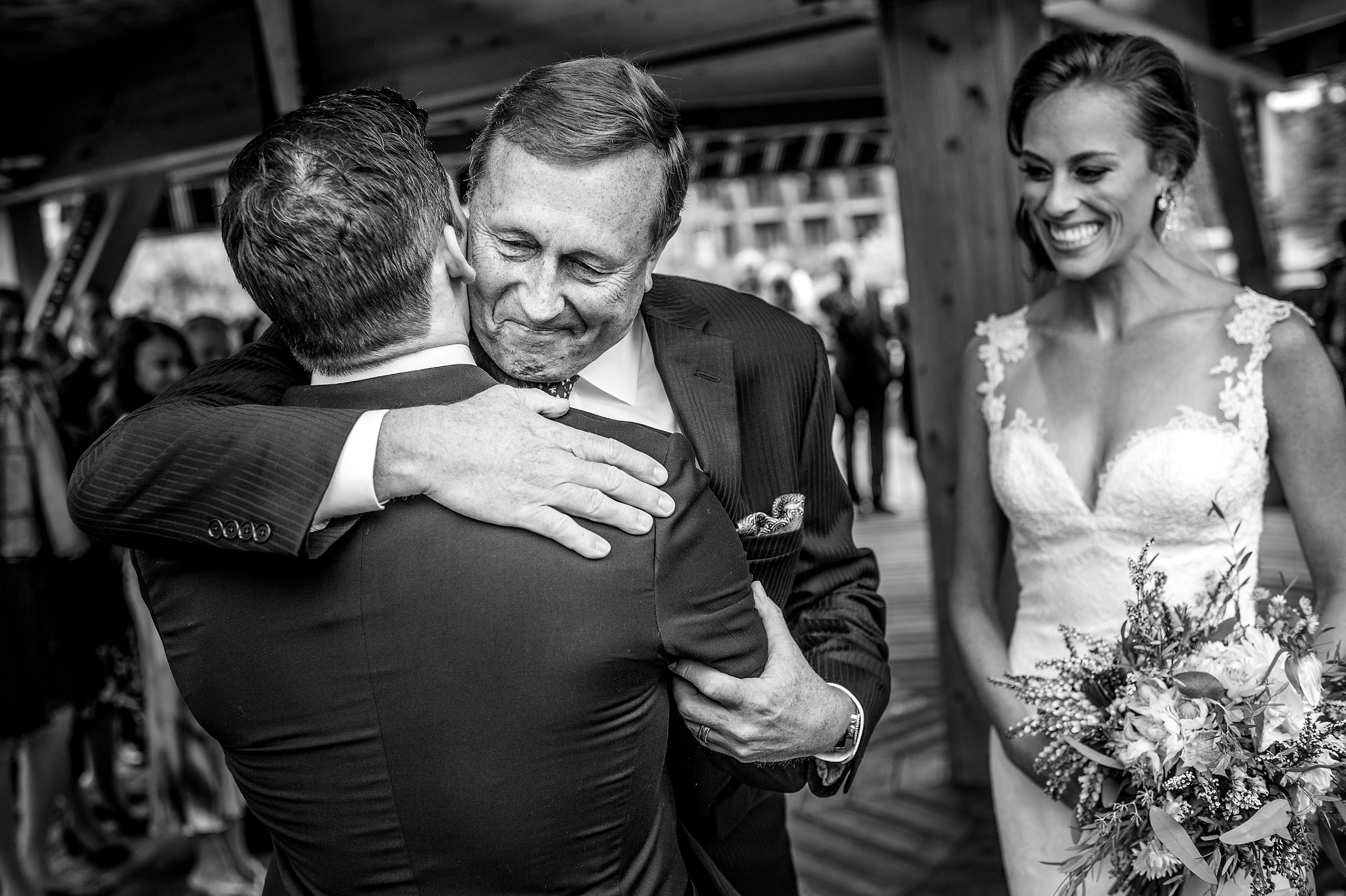 a bride's dad giving the groom a big hug at Priddis Azuridge Wedding by sean leblanc