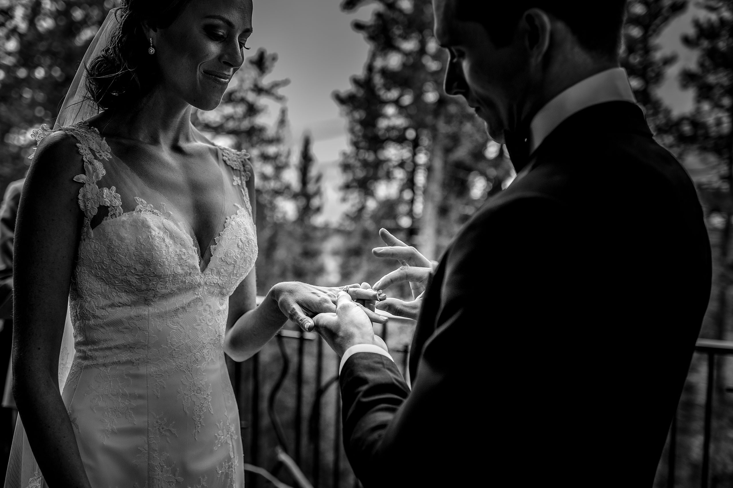 a groom placing a wedding ring on his bride's finger at Priddis Azuridge Wedding by sean leblanc