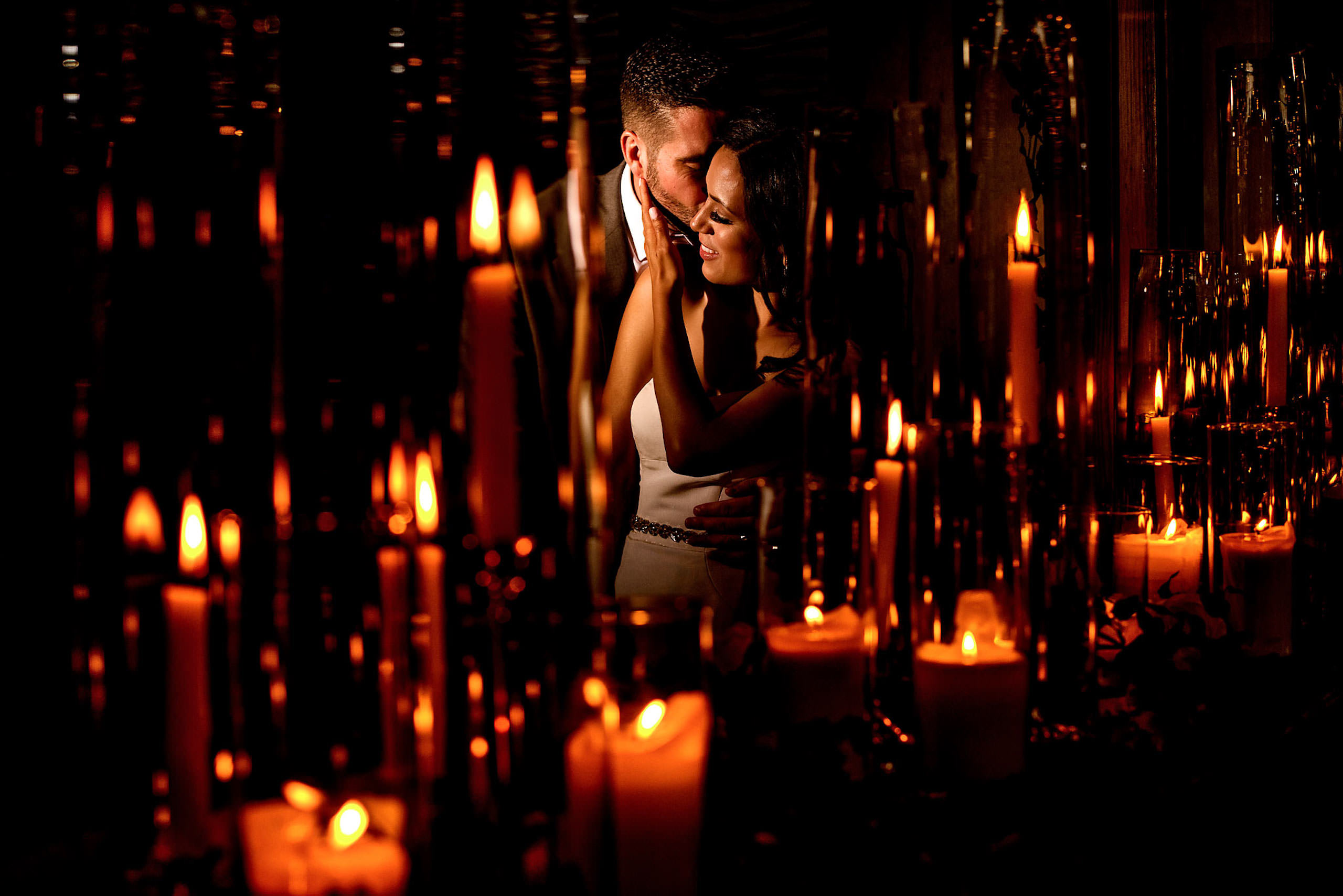 a bride and groom embracing in front of candles by calgary sean leblanc wedding photographers