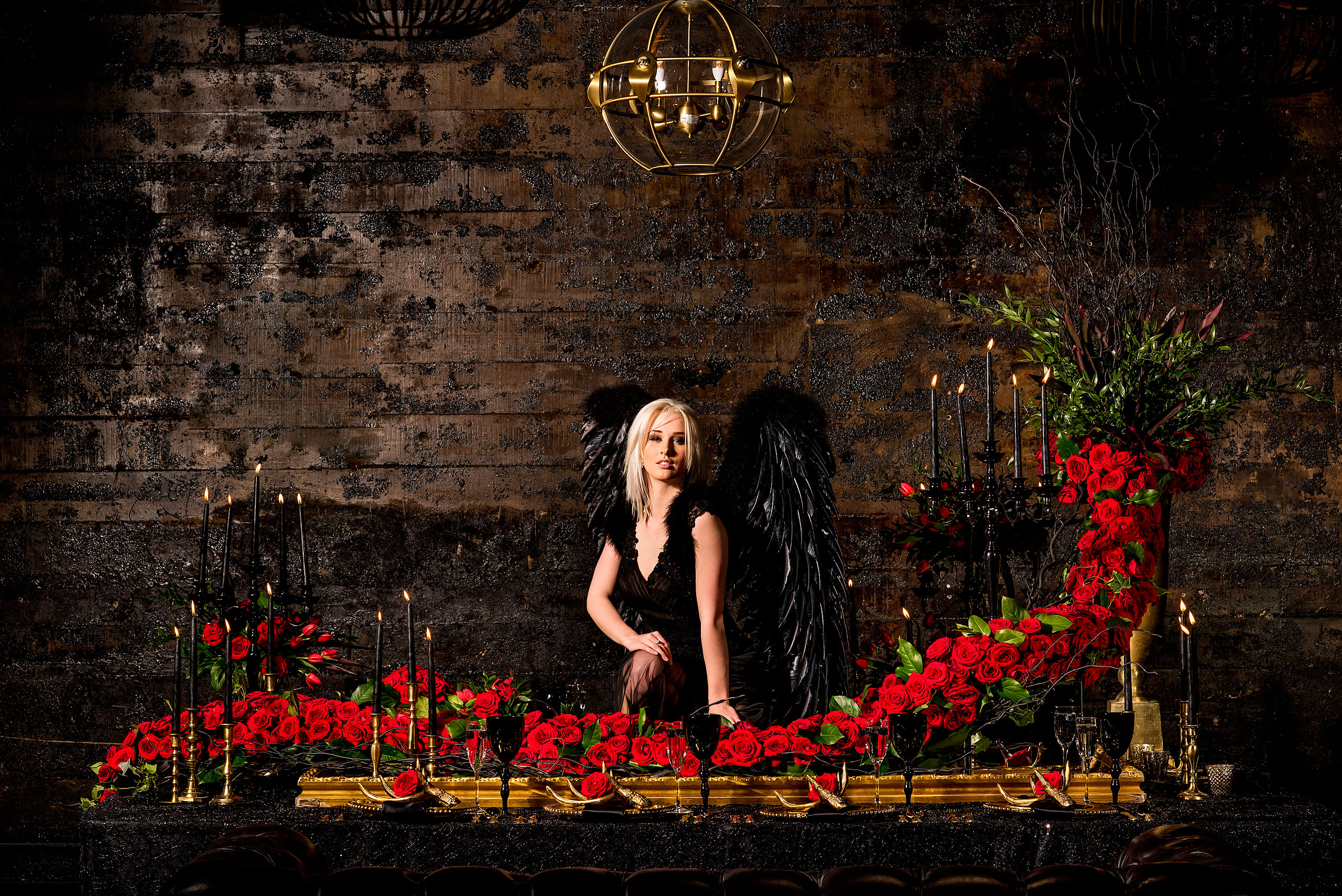 a model wearing a black dress sitting on a mirror behind roses by calgary confetti fashion photographer sean leblanc