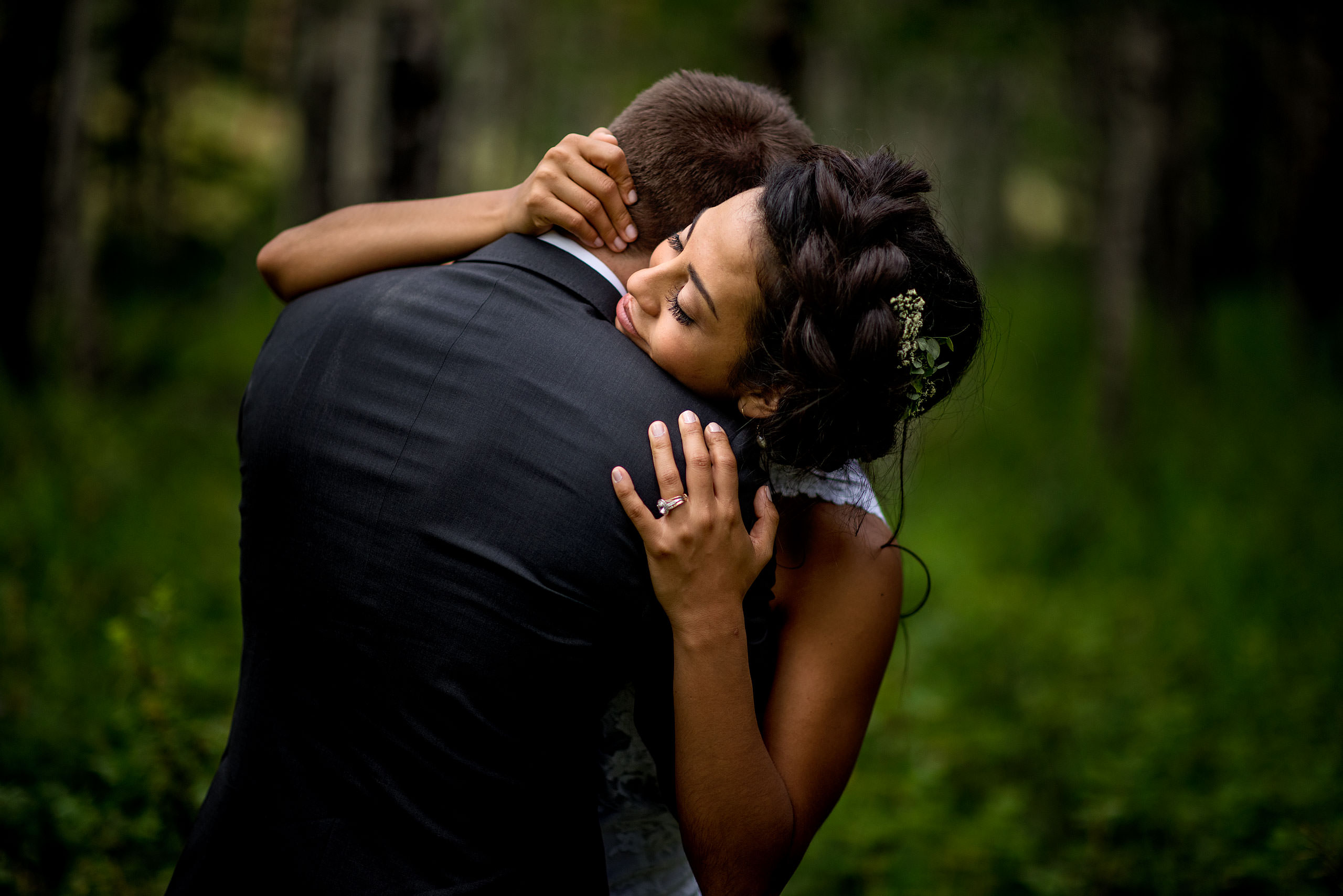 a bride giving her groom a big hug in the forest by calgary wedding photographer sean leblanc