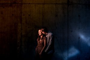 an engaged couple holding each other in front of a concrete wall by calgary engagement photographer sean leblanc