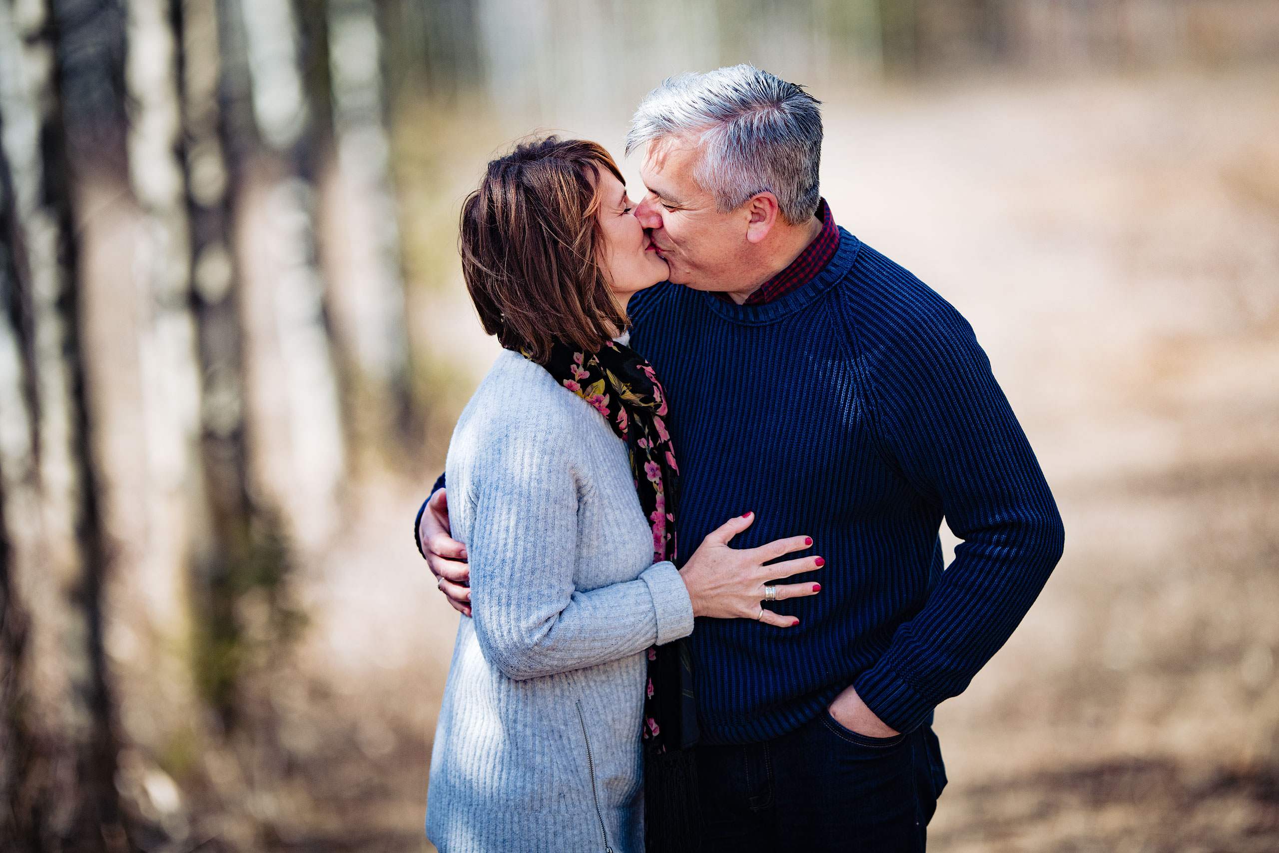 a husband and wife kissing in the trees by Canmore Family Photographer Sean LeBlanc