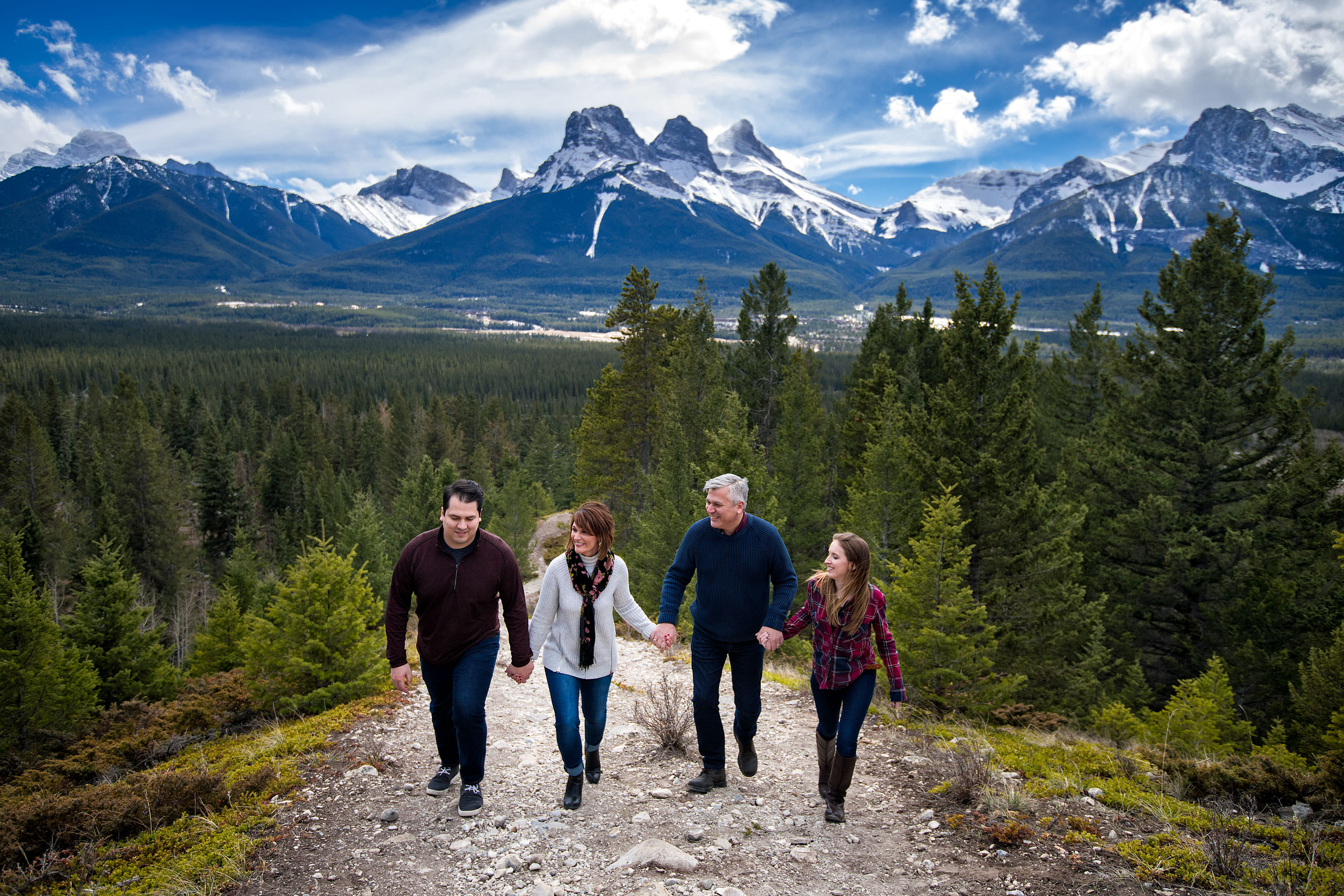 a family holding hands walking up a mountain by Canmore Family Photographer Sean LeBlanc