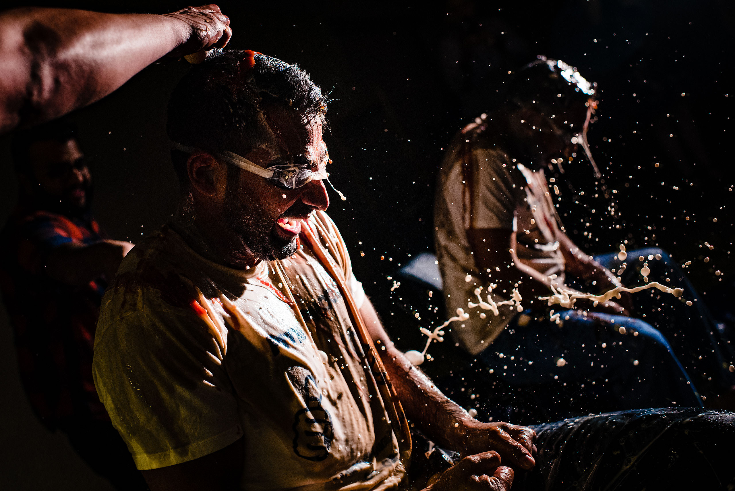 two Indian men getting milk poured on them by Calgary Banff Wedding Photographer Sean LeBlanc