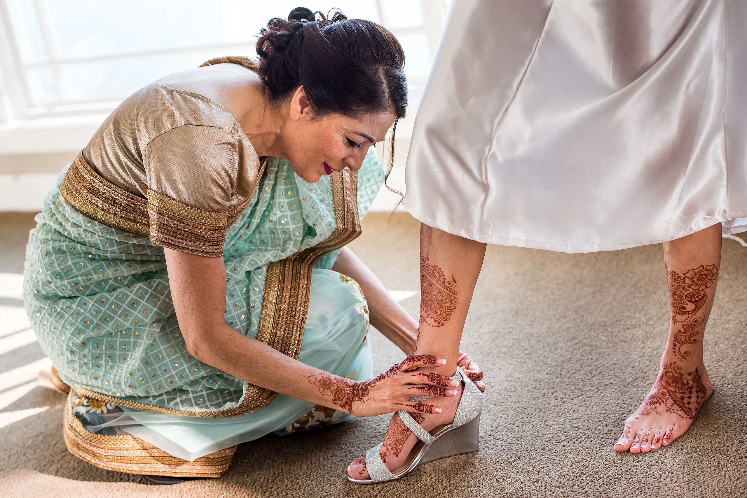 an Indian mom helping put on her daughters wedding shoes by Calgary Banff Wedding Photographer Sean LeBlanc