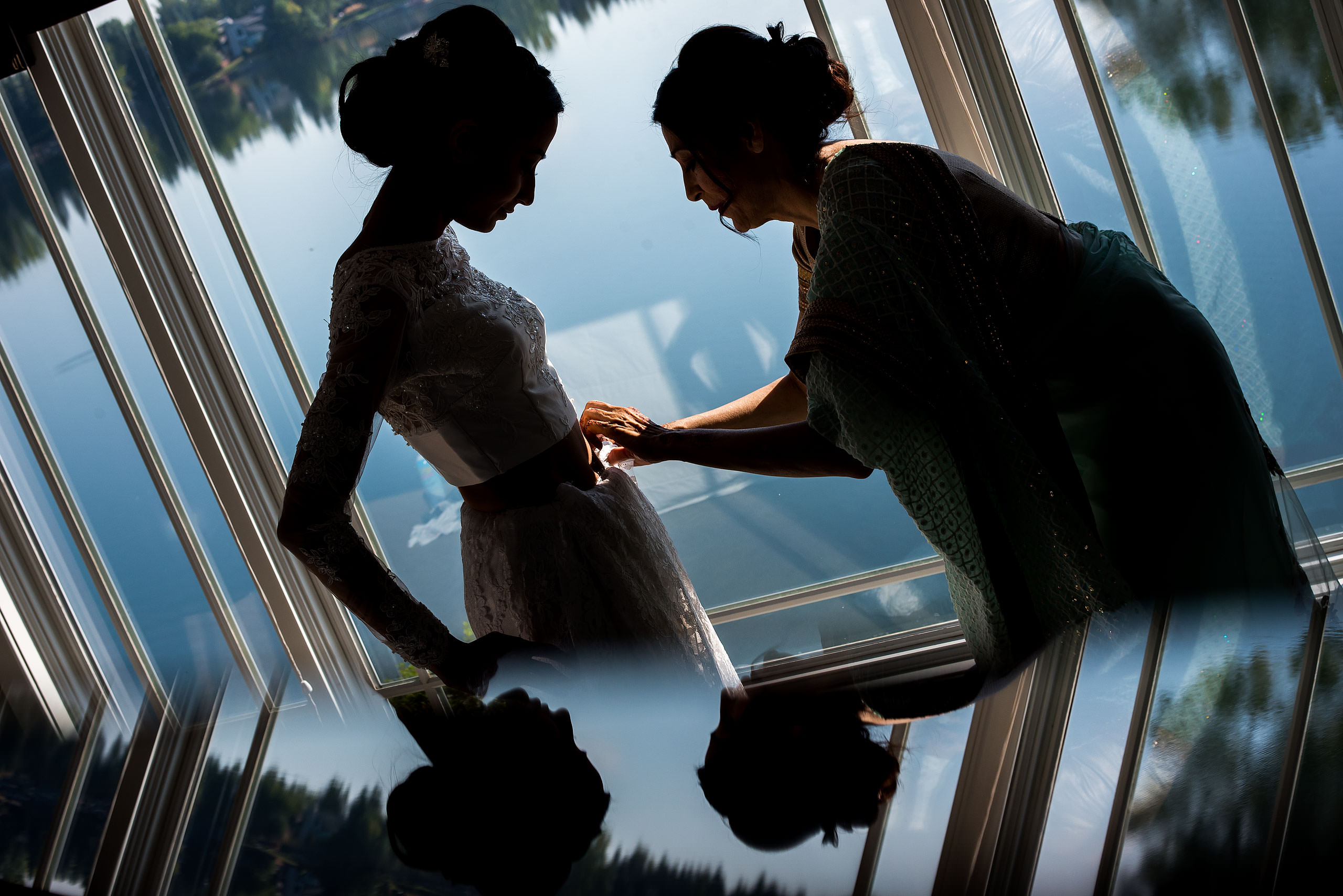 a silhouette of a mom helping her daughter with her wedding dress by Calgary Banff Wedding Photographer Sean LeBlanc