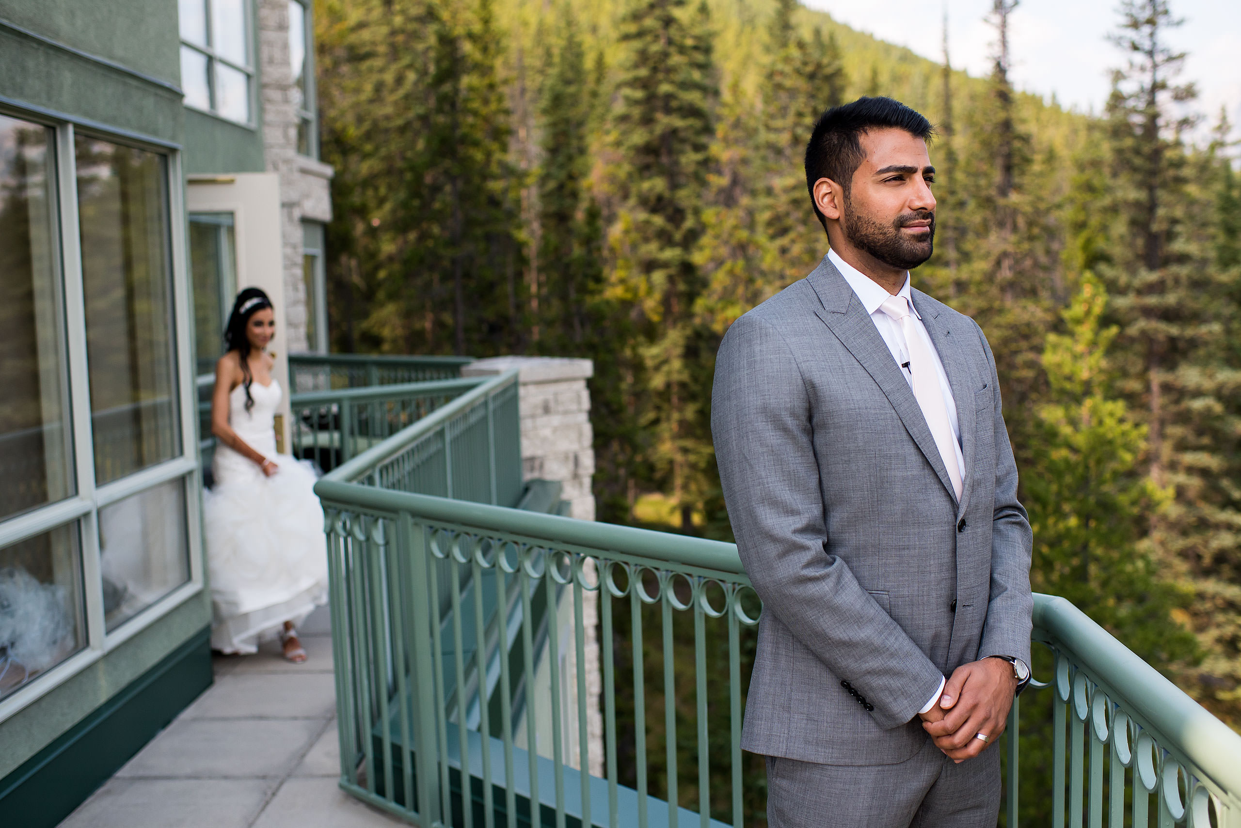 a groom waiting on a balcony at the Rimrock hotel for his bride by Calgary Banff Wedding Photographer Sean LeBlanc