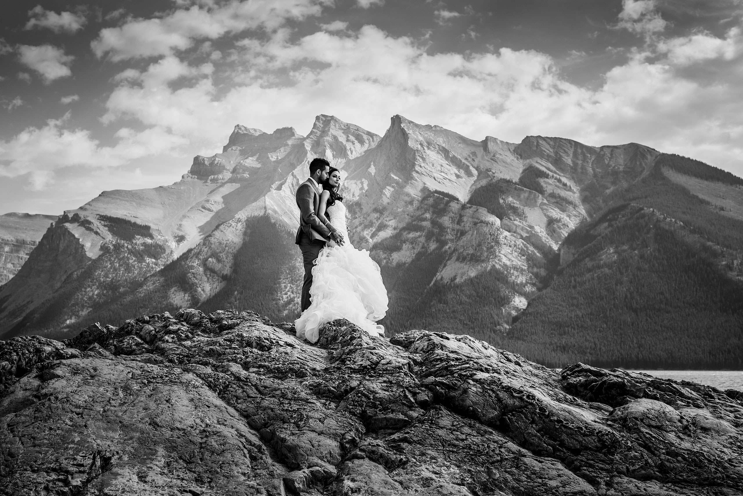 a bride and groom embracing on top of a mountain by Calgary Banff Wedding Photographer Sean LeBlanc