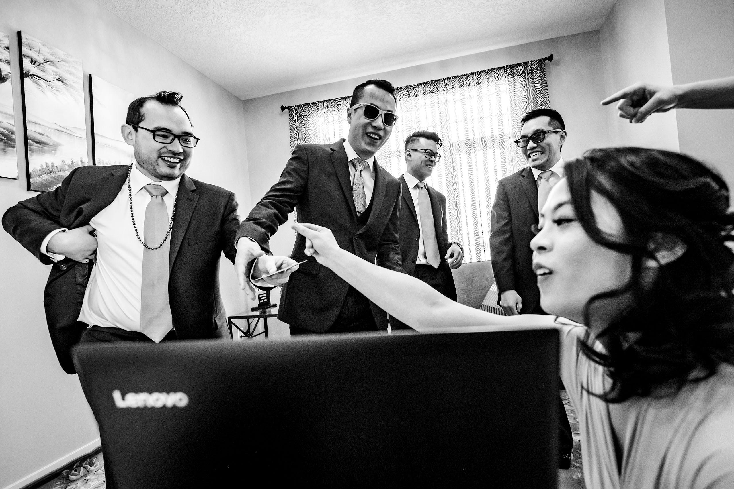 groomsmen laughing in at a computer screen at a calgary lake house wedding by calgary wedding photographer sean leblanc photography