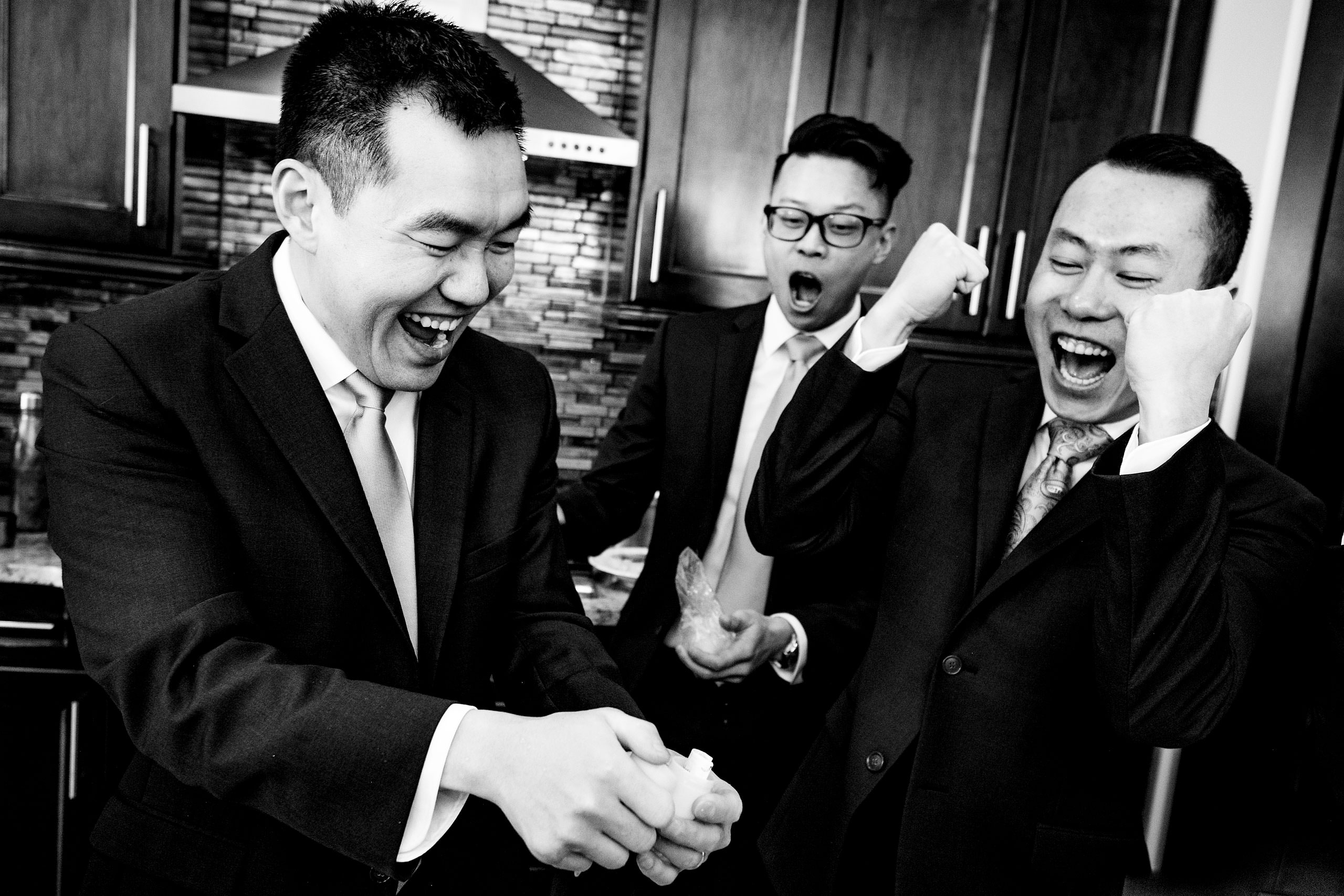 three groomsmen cheering at a piece of paper at a calgary lake house wedding by calgary wedding photographer sean leblanc photography