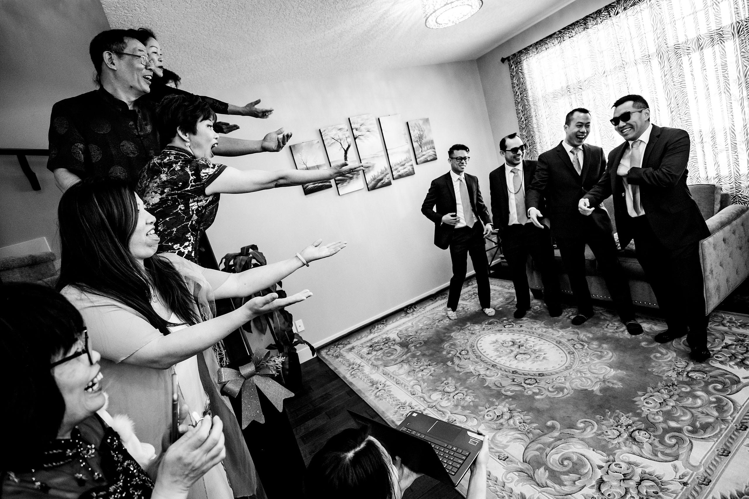 a group of people laughing at four groomsmen at a calgary lake house wedding by calgary wedding photographer sean leblanc photography