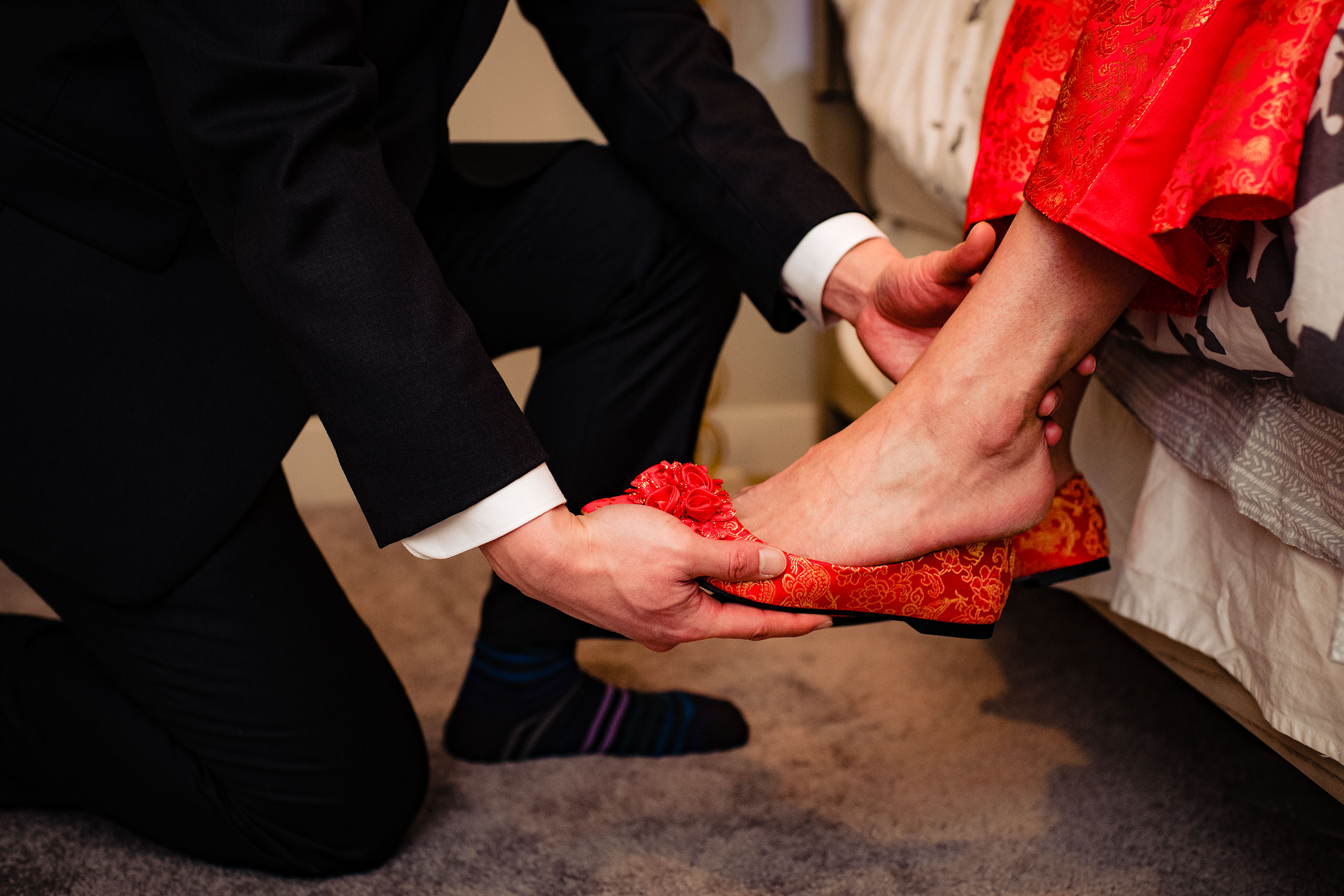 a groom putting on a bride's shoe for their calgary lake house wedding by calgary wedding photographer sean leblanc photography