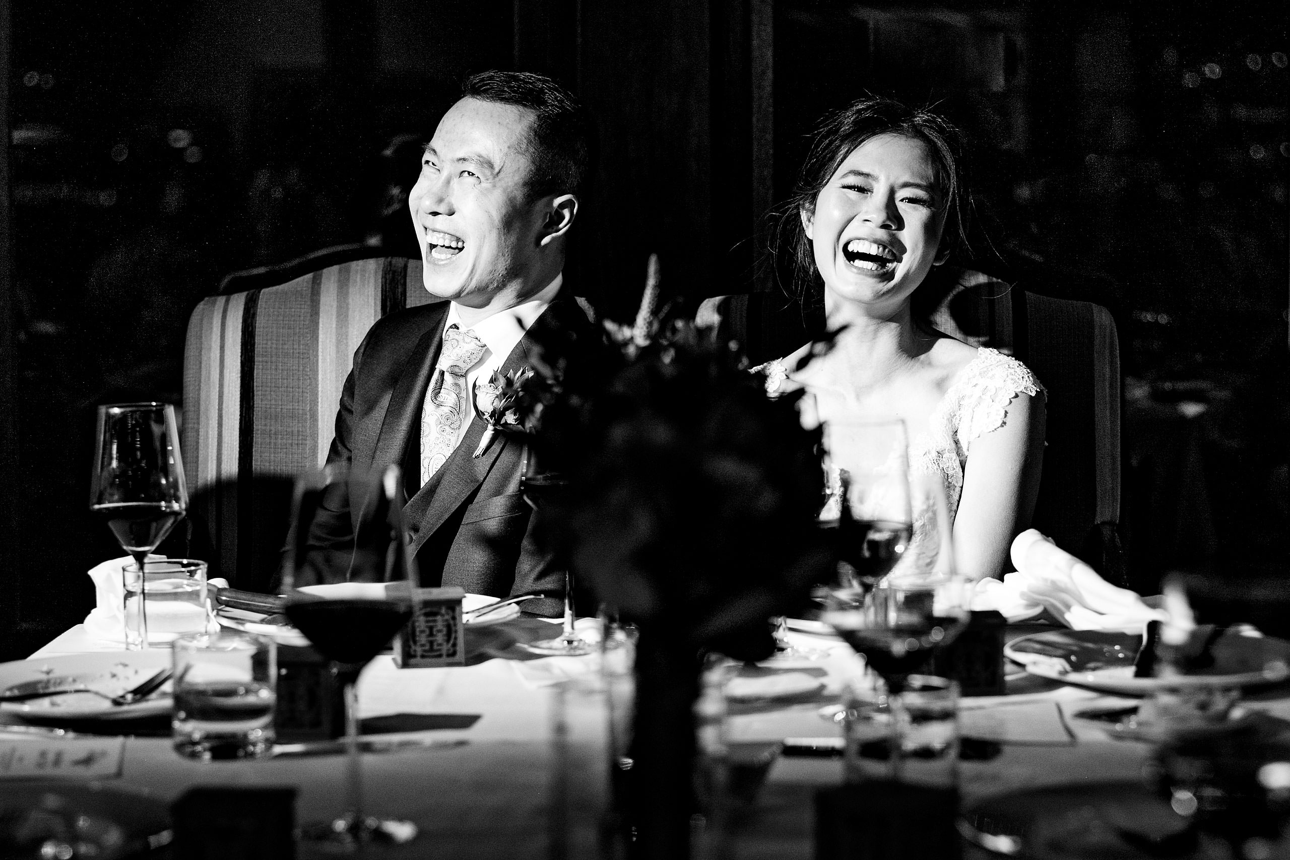 a bride and groom laughing at their reception at their calgary lake house wedding by calgary wedding photographer sean leblanc photography