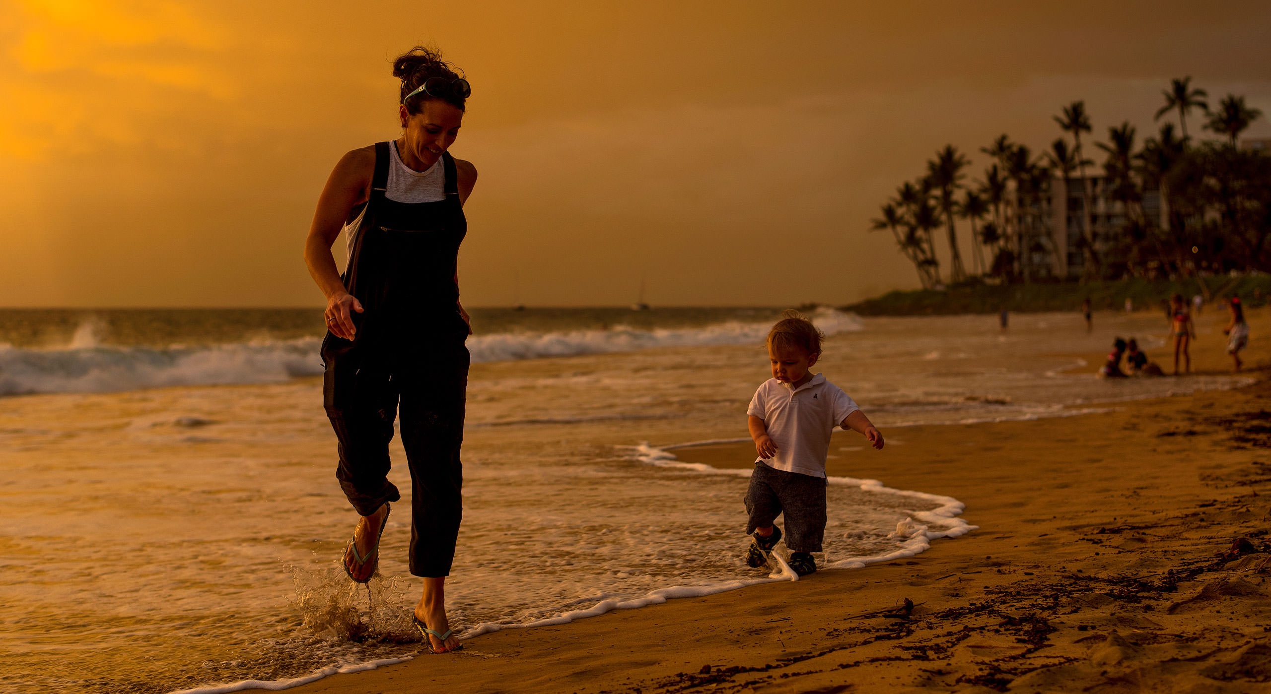 a women and her young son walking along the beach in Hawaii photographed by family photographer Sean LeBlanc